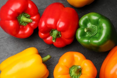 Photo of Fresh colorful bell peppers on dark gray table, flat lay