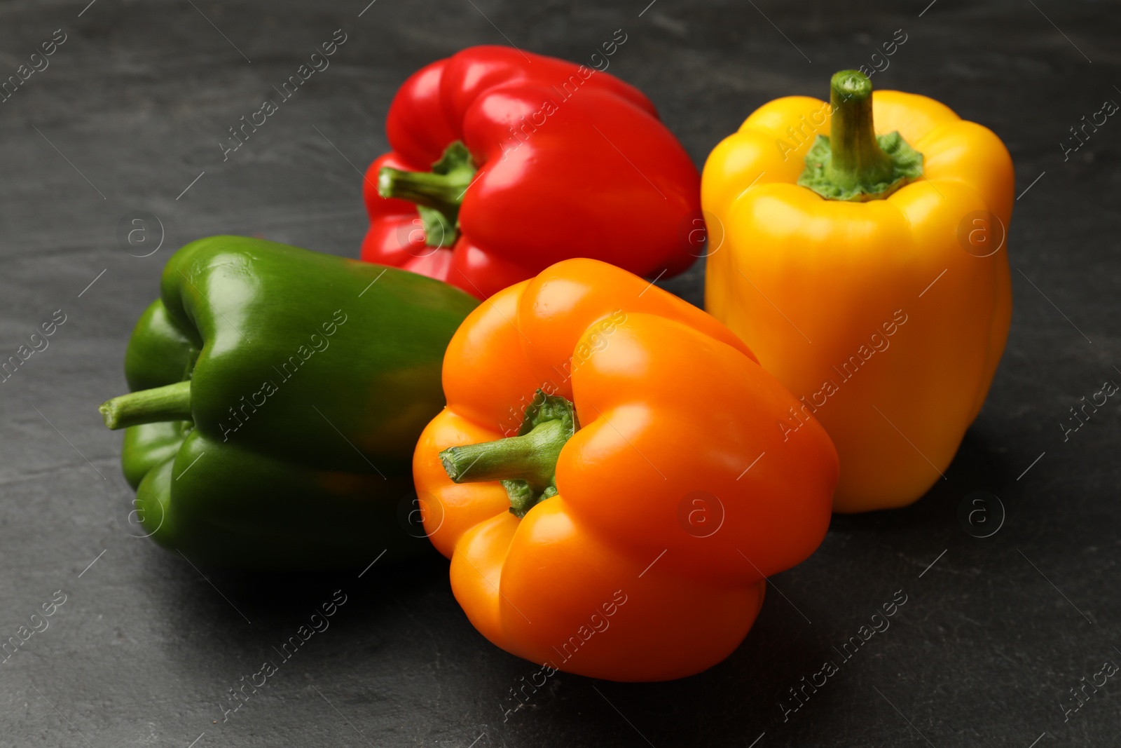 Fresh colorful bell peppers on black textured table, closeup Photo of Fresh colorful bell peppers on black textured table, closeup