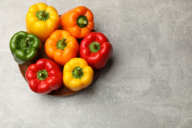Photo of Fresh colorful bell peppers on gray textured table, top view. Space for text