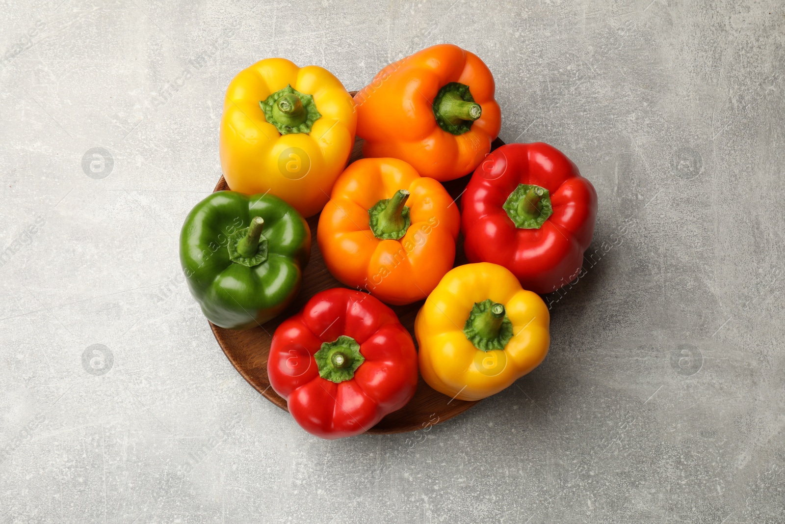 Photo of Fresh colorful bell peppers on gray textured table, top view