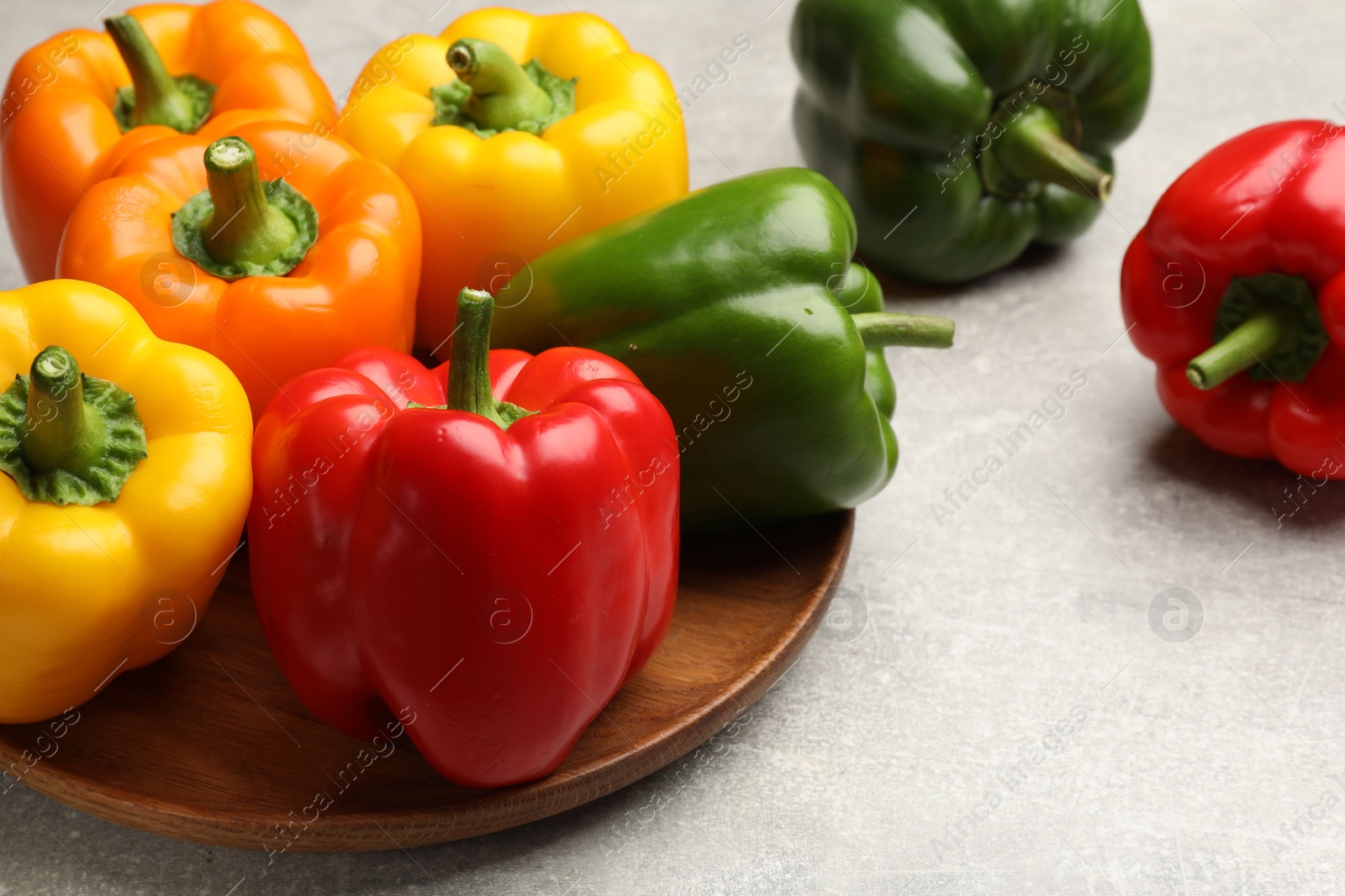 Photo of Fresh colorful bell peppers on gray textured table, closeup