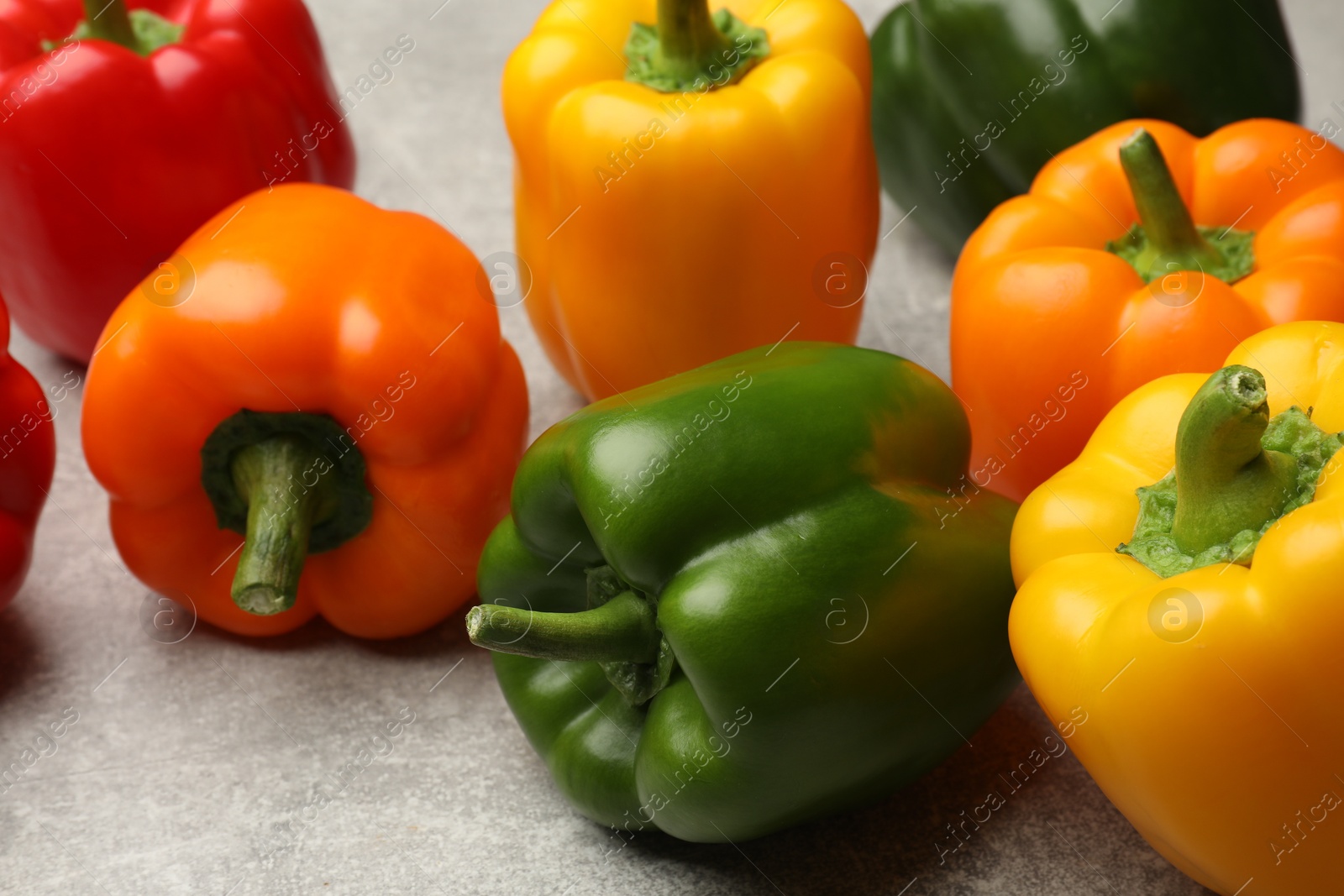 Photo of Fresh colorful bell peppers on gray textured table, closeup