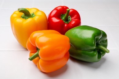 Photo of Fresh colorful bell peppers on white table, closeup