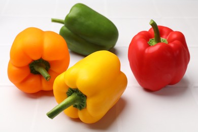 Photo of Fresh colorful bell peppers on white table, closeup