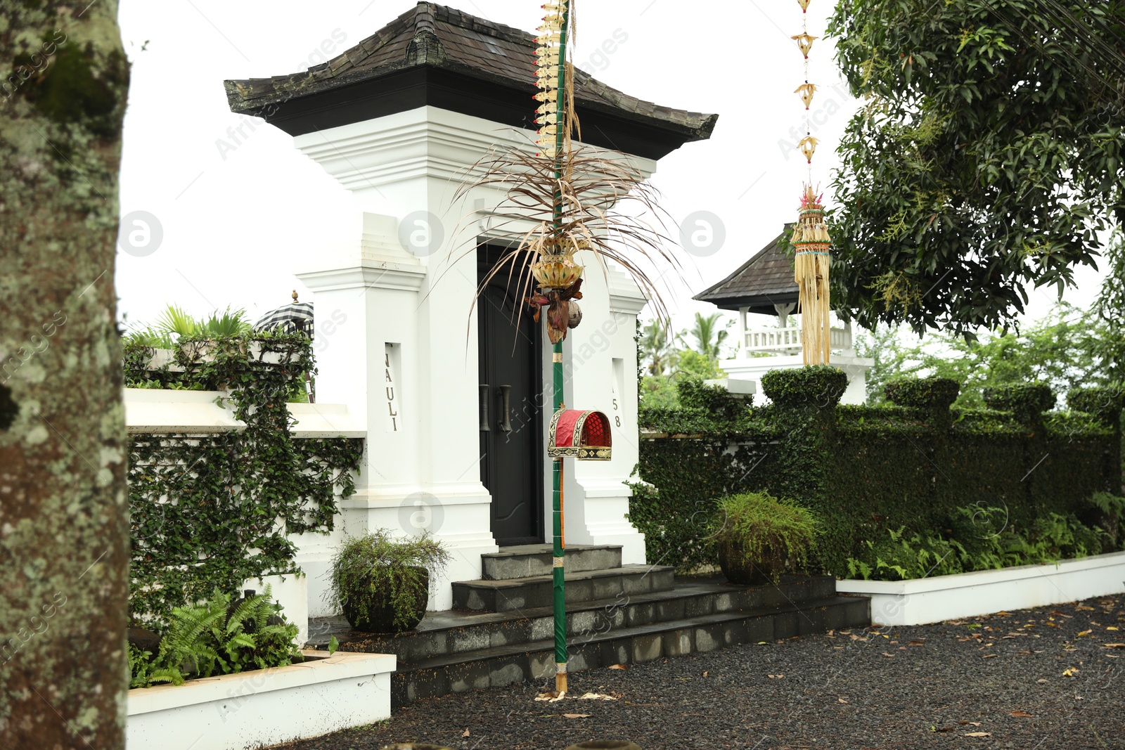 Photo of Bali, Indonesia - May 11, 2025: Entrance of yard, traditional penjor and green plants outdoors