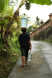 Photo of Bali, Indonesia - May 11, 2025: Woman carrying water on her head outdoors