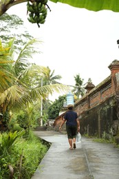Photo of Bali, Indonesia - May 11, 2025: Woman carrying water on her head outdoors