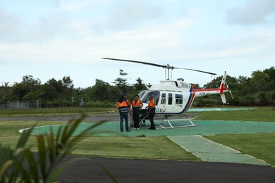 Photo of Indonesia, Bali - May 13, 2025: Helicopter crew near aircraft at heliport
