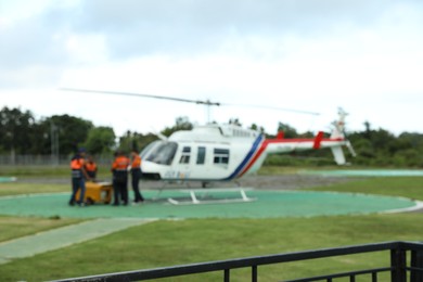 Photo of Blurred view of helicopter crew near aircraft at heliport