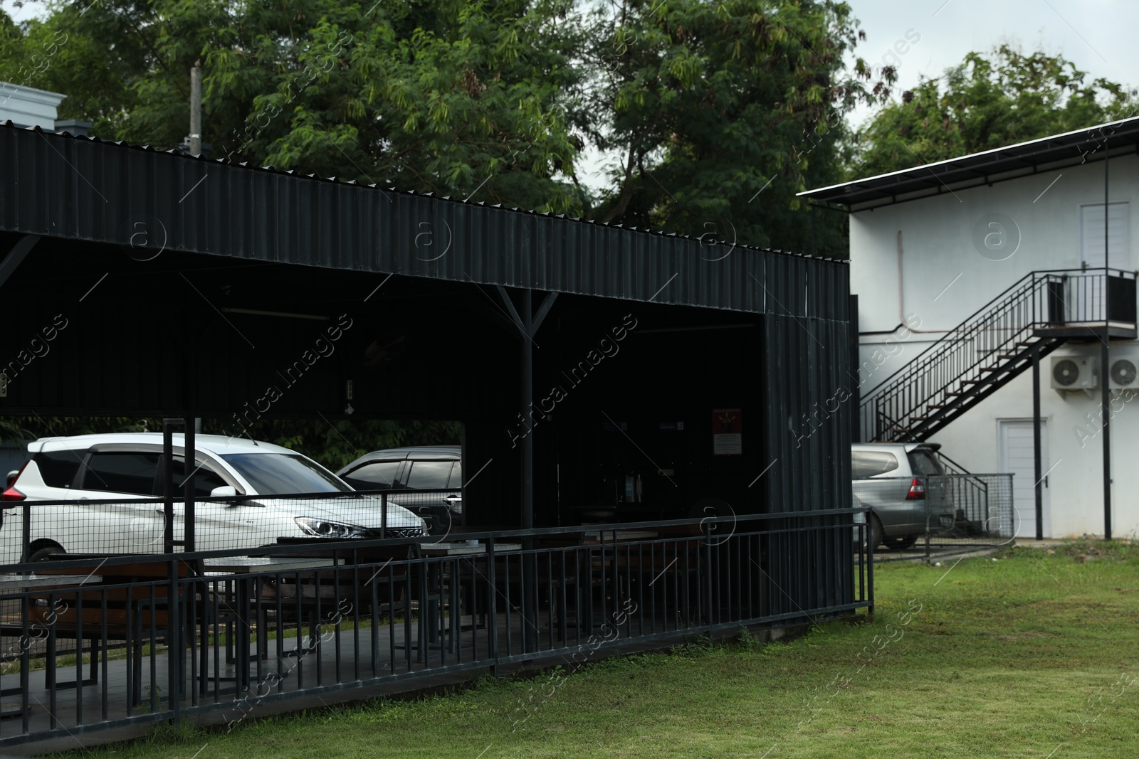 Photo of Different cars parked near building, view through outdoor structure