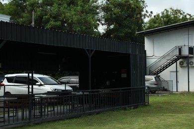 Photo of Different cars parked near building, view through outdoor structure