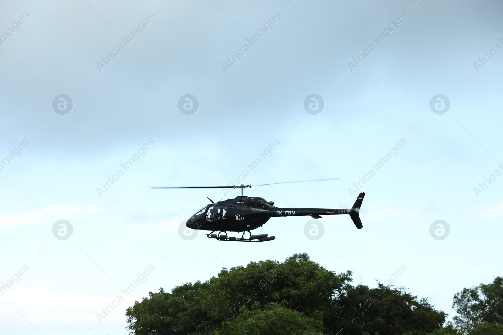 Indonesia, Bali - May 13, 2025: Black helicopter flying in sky Photo of Indonesia, Bali - May 13, 2025: Black helicopter flying in sky