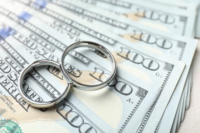 Photo of Two silver wedding rings and dollar banknotes on white table, closeup