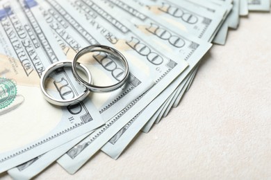 Photo of Two silver wedding rings and dollar banknotes on white table, closeup. Space for text
