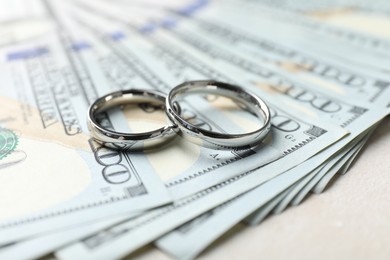 Photo of Two silver wedding rings and dollar banknotes on white table, closeup