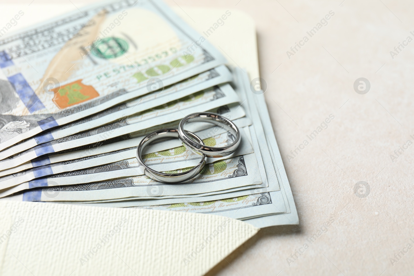 Photo of Two silver wedding rings, dollar banknotes and envelope on white table, closeup. Space for text