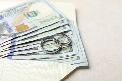 Photo of Two silver wedding rings, dollar banknotes and envelope on white table, closeup. Space for text