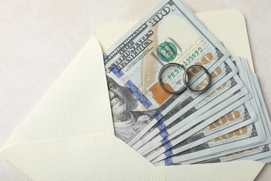 Photo of Two silver wedding rings, dollar banknotes and envelope on white table, top view