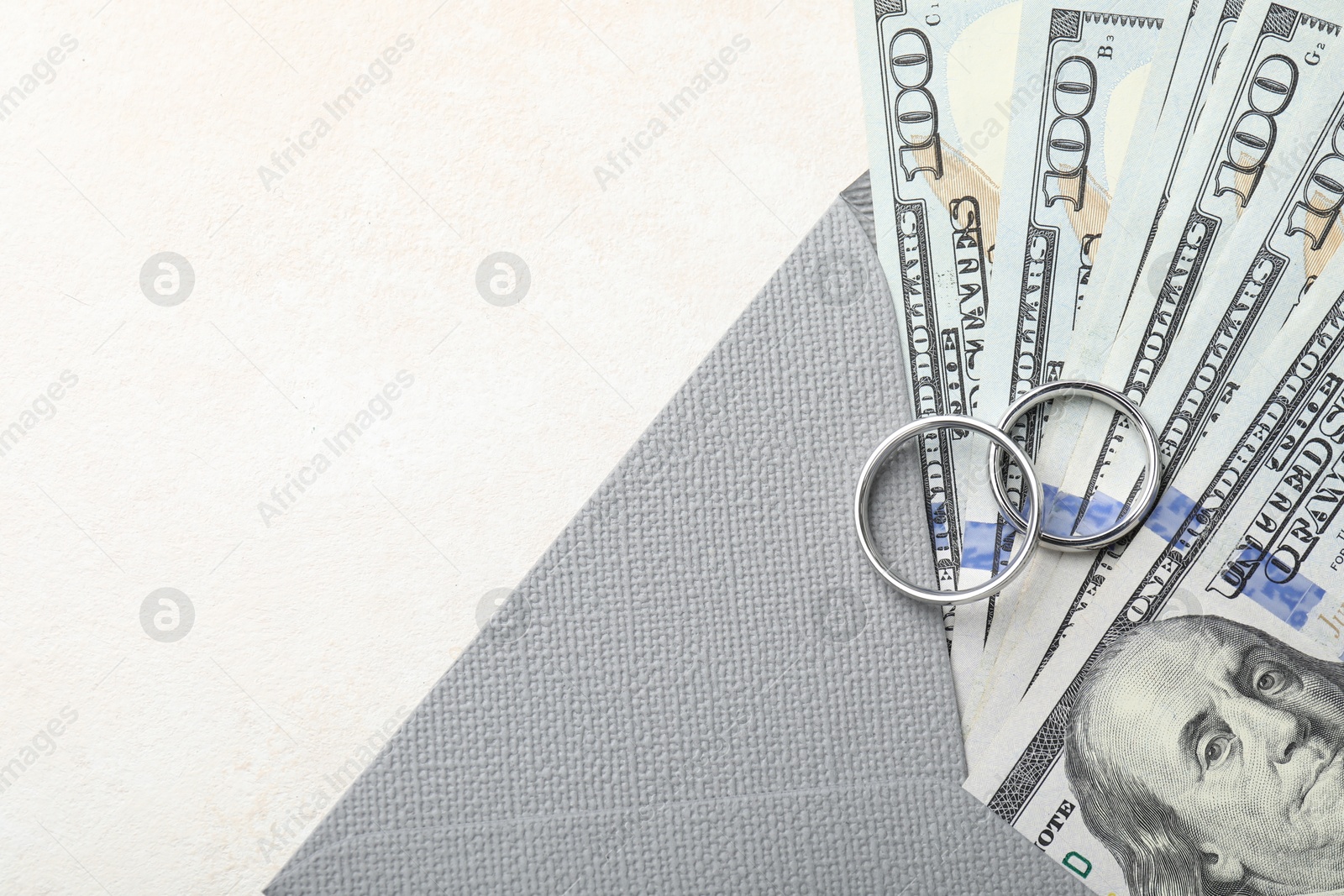 Two silver wedding rings, dollar banknotes and envelope on white table, top view. Space for text Photo of Two silver wedding rings, dollar banknotes and envelope on white table, top view. Space for text