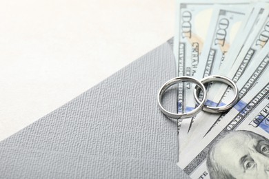 Photo of Two silver wedding rings, dollar banknotes and envelope on white table, closeup. Space for text