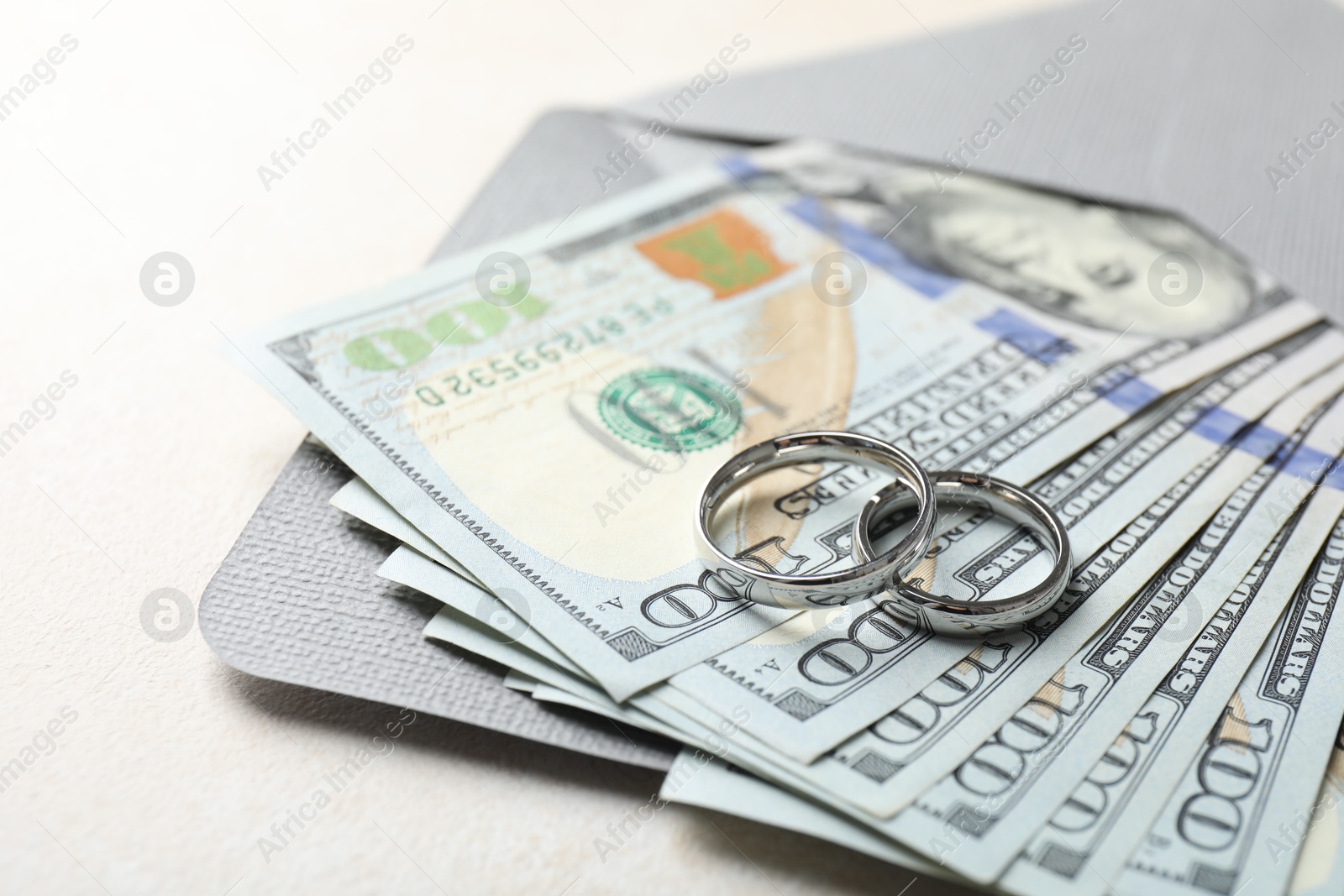 Photo of Two silver wedding rings, dollar banknotes and envelope on white table, closeup