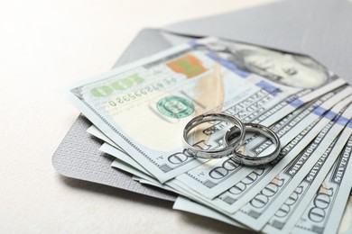 Photo of Two silver wedding rings, dollar banknotes and envelope on white table, closeup