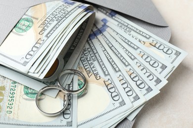 Photo of Two silver wedding rings, dollar banknotes and envelope on white table, closeup