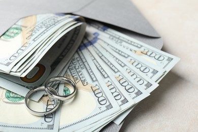 Photo of Two silver wedding rings, dollar banknotes and envelope on white table, closeup