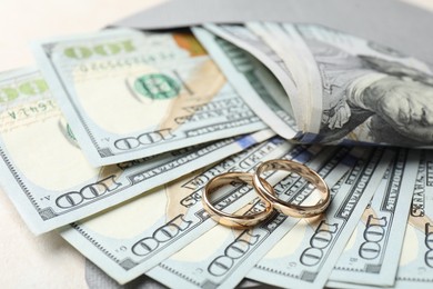 Photo of Two gold wedding rings, dollar banknotes and envelope on white table, closeup