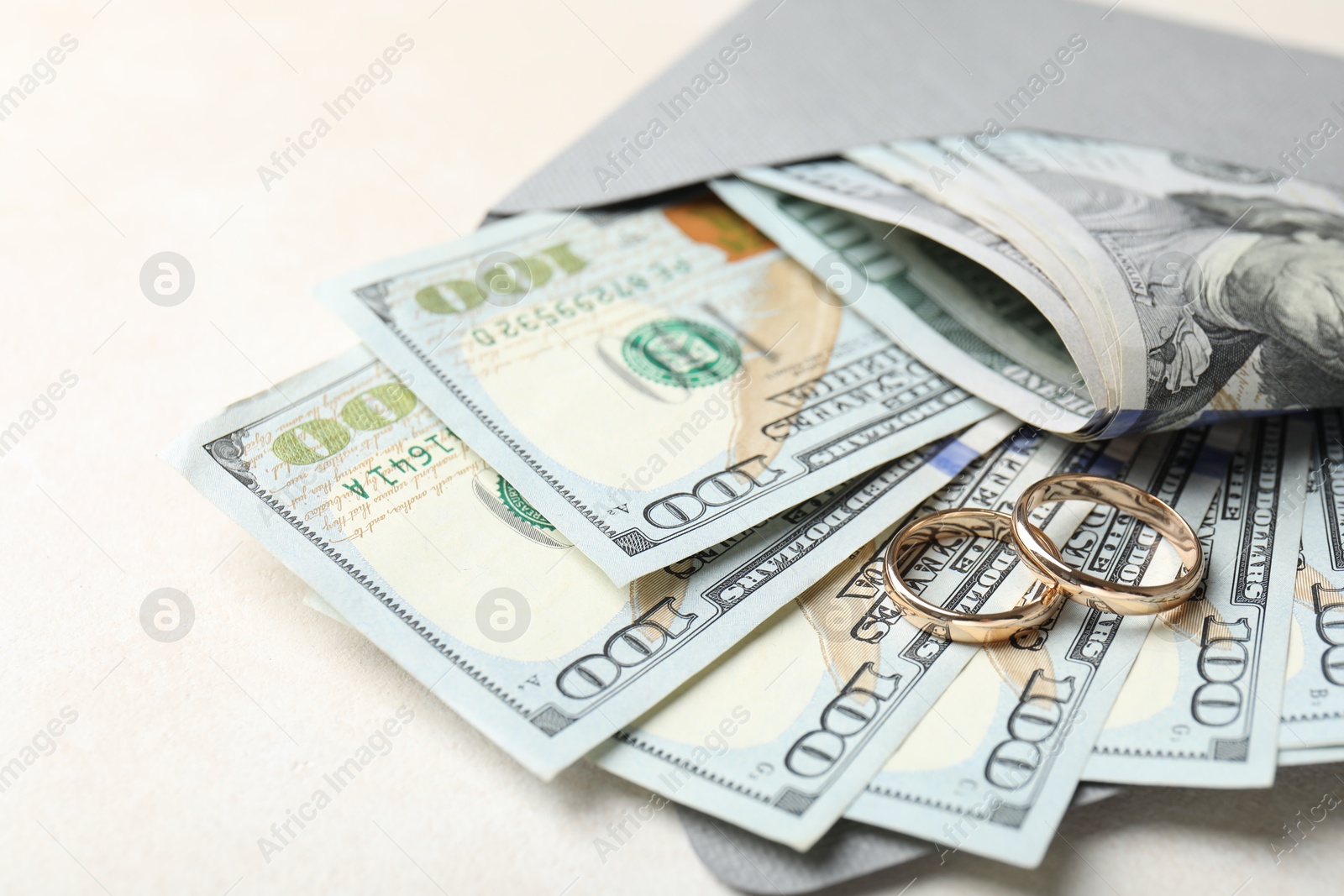 Photo of Two gold wedding rings, dollar banknotes and envelope on white table, closeup