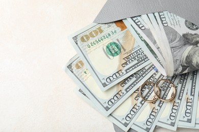 Photo of Two gold wedding rings, dollar banknotes and envelope on white table, top view. Space for text