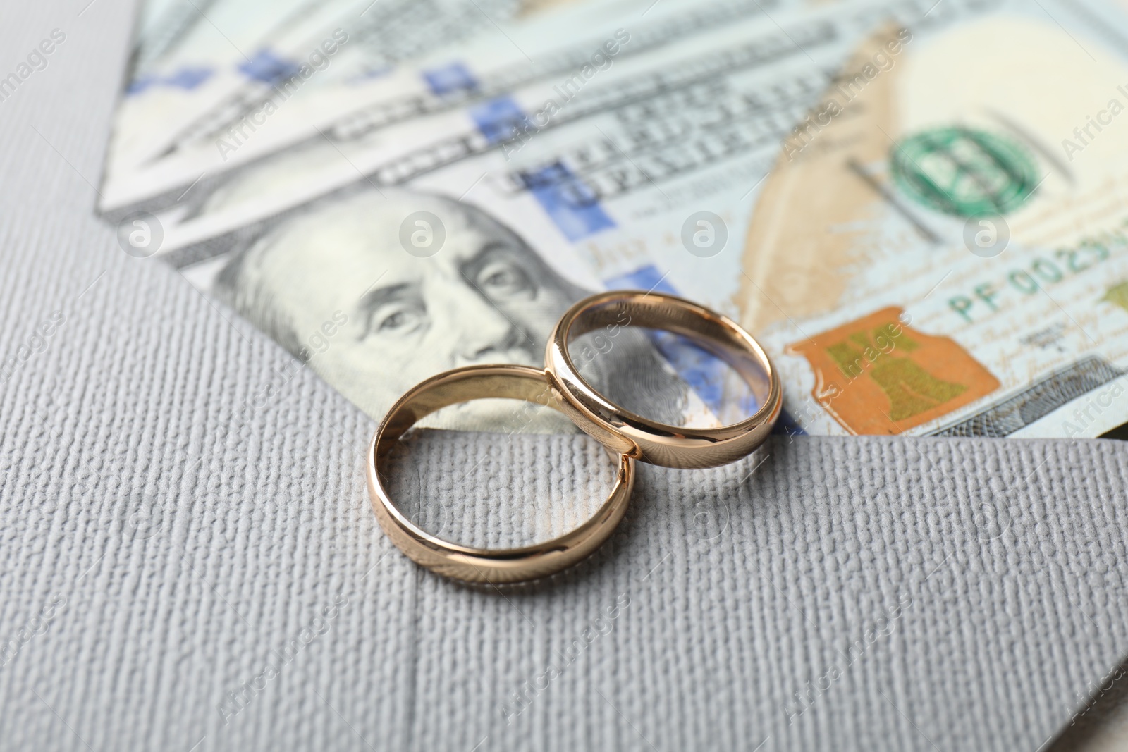 Photo of Two gold wedding rings, dollar banknotes and envelope, closeup