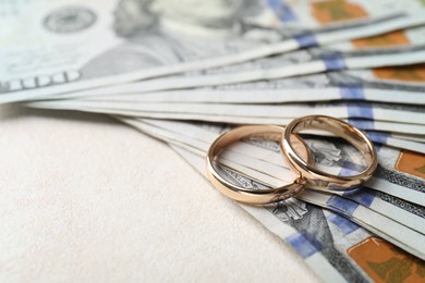 Photo of Two gold wedding rings and dollar banknotes on white table, closeup. Space for text