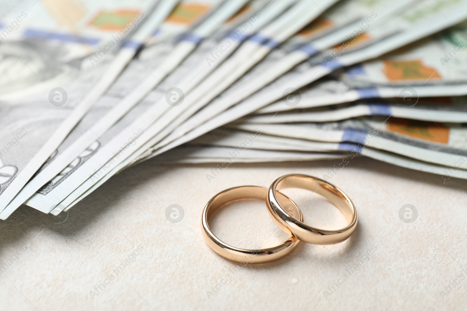 Two gold wedding rings and dollar banknotes on white table, closeup Photo of Two gold wedding rings and dollar banknotes on white table, closeup