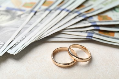 Photo of Two gold wedding rings and dollar banknotes on white table, closeup
