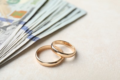 Photo of Two gold wedding rings and dollar banknotes on white table, closeup. Space for text