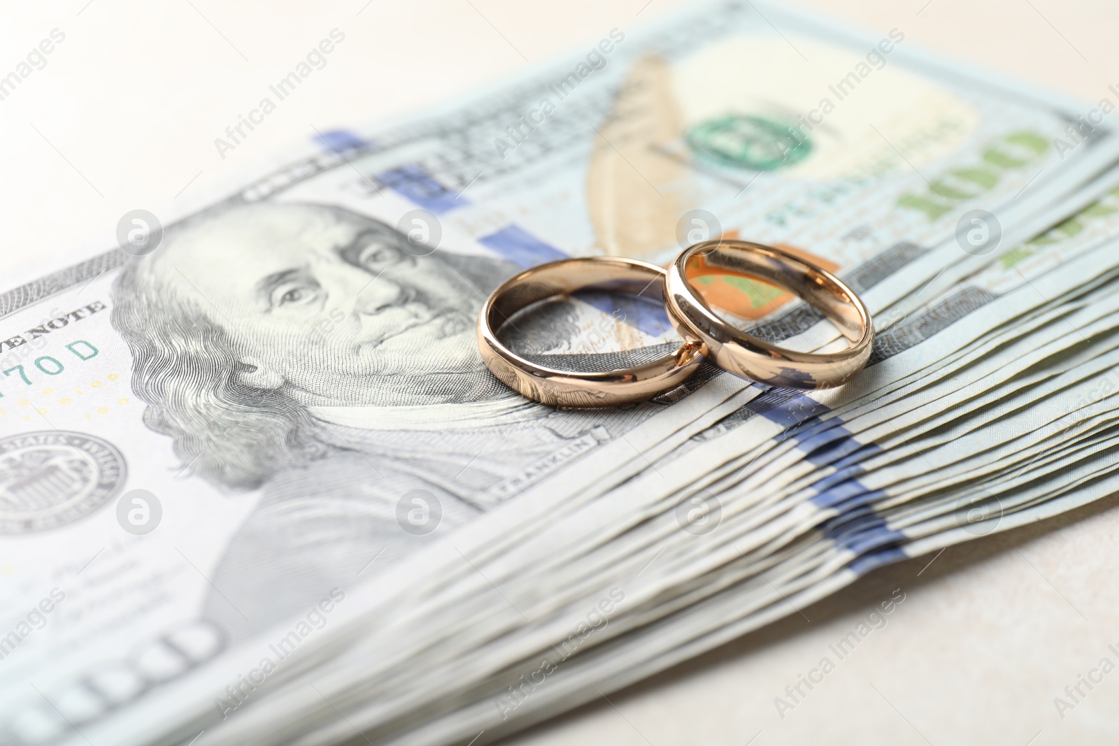 Photo of Two gold wedding rings and dollar banknotes on white table, closeup