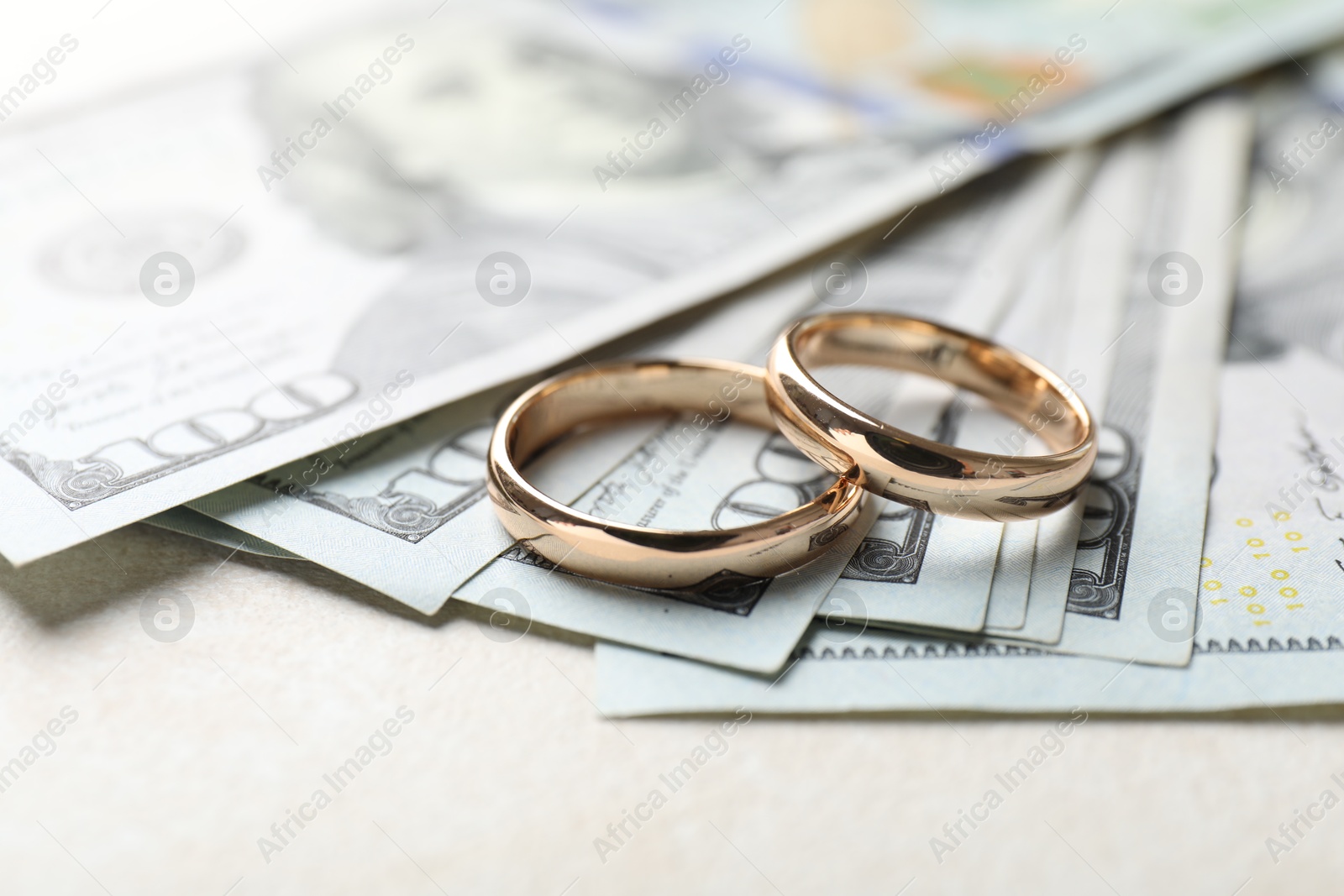 Photo of Two gold wedding rings and dollar banknotes on white table, closeup