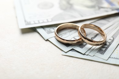 Photo of Two gold wedding rings and dollar banknotes on white table, closeup. Space for text