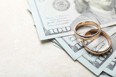 Photo of Two gold wedding rings and dollar banknotes on white table, closeup. Space for text