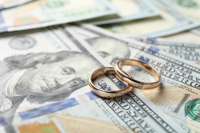 Photo of Two gold wedding rings on dollar banknotes, closeup