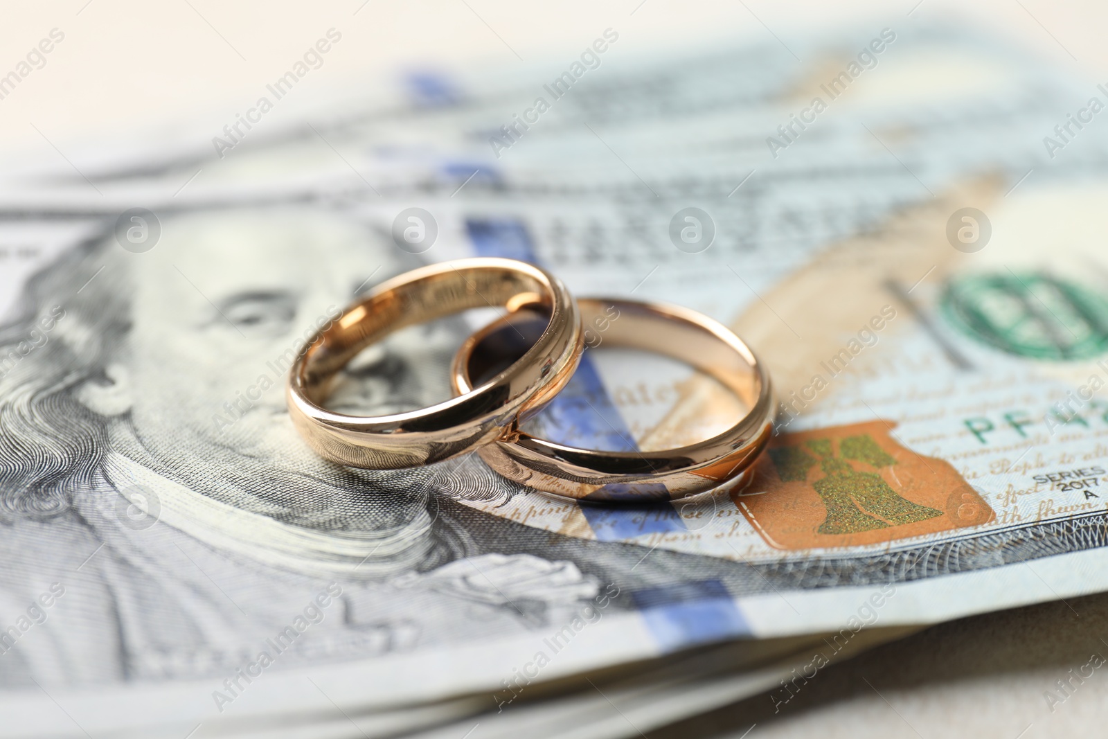 Photo of Two gold wedding rings and dollar banknotes on white table, closeup