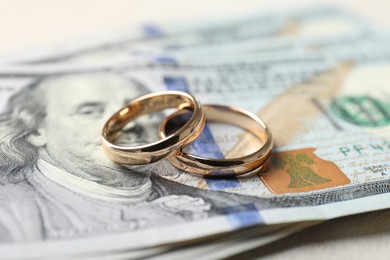 Photo of Two gold wedding rings and dollar banknotes on white table, closeup