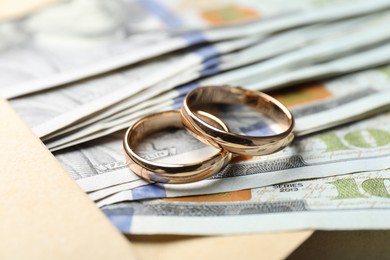 Photo of Two gold wedding rings, dollar banknotes and envelope, closeup