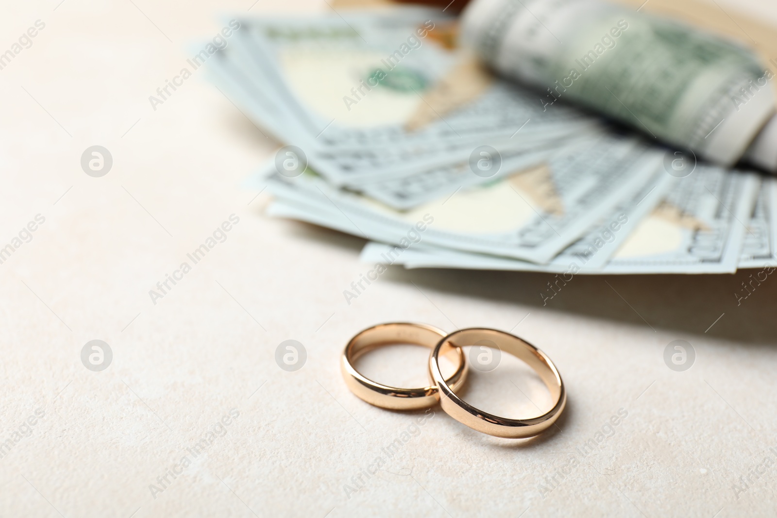Photo of Two gold wedding rings and dollar banknotes on white table, closeup. Space for text