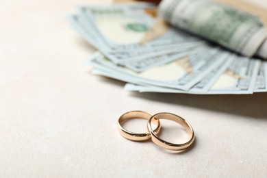 Photo of Two gold wedding rings and dollar banknotes on white table, closeup. Space for text