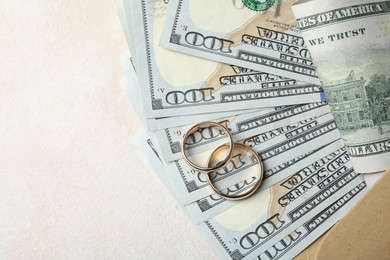 Photo of Two gold wedding rings, dollar banknotes and envelope on white table, top view. Space for text