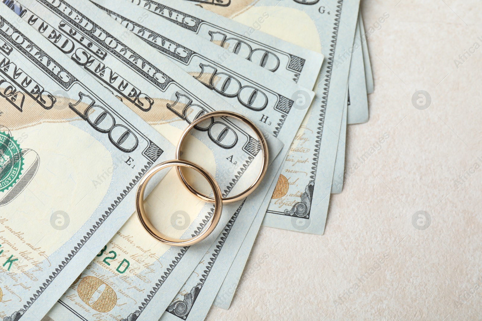 Two gold wedding rings and dollar banknotes on white table, top view. Space for text Photo of Two gold wedding rings and dollar banknotes on white table, top view. Space for text