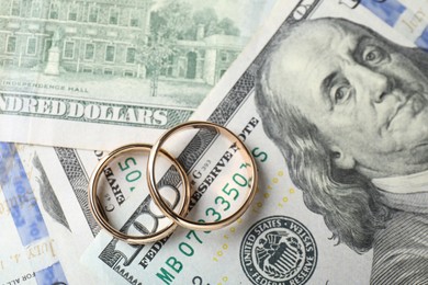 Photo of Two gold wedding rings on dollar banknotes, top view