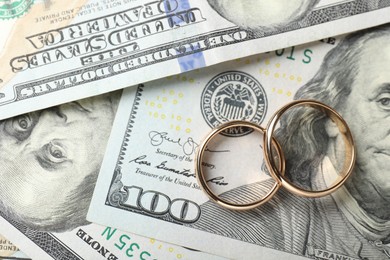 Photo of Two gold wedding rings on dollar banknotes, top view